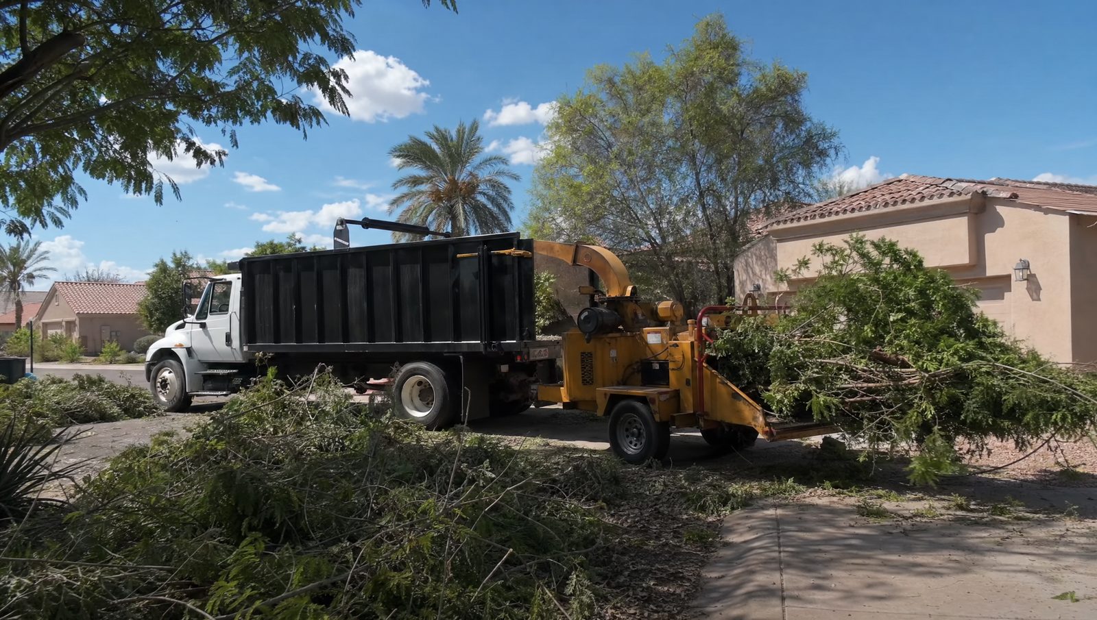 Landscaping crew truck and chipper clearing storm debris after a Phoenix monsoon