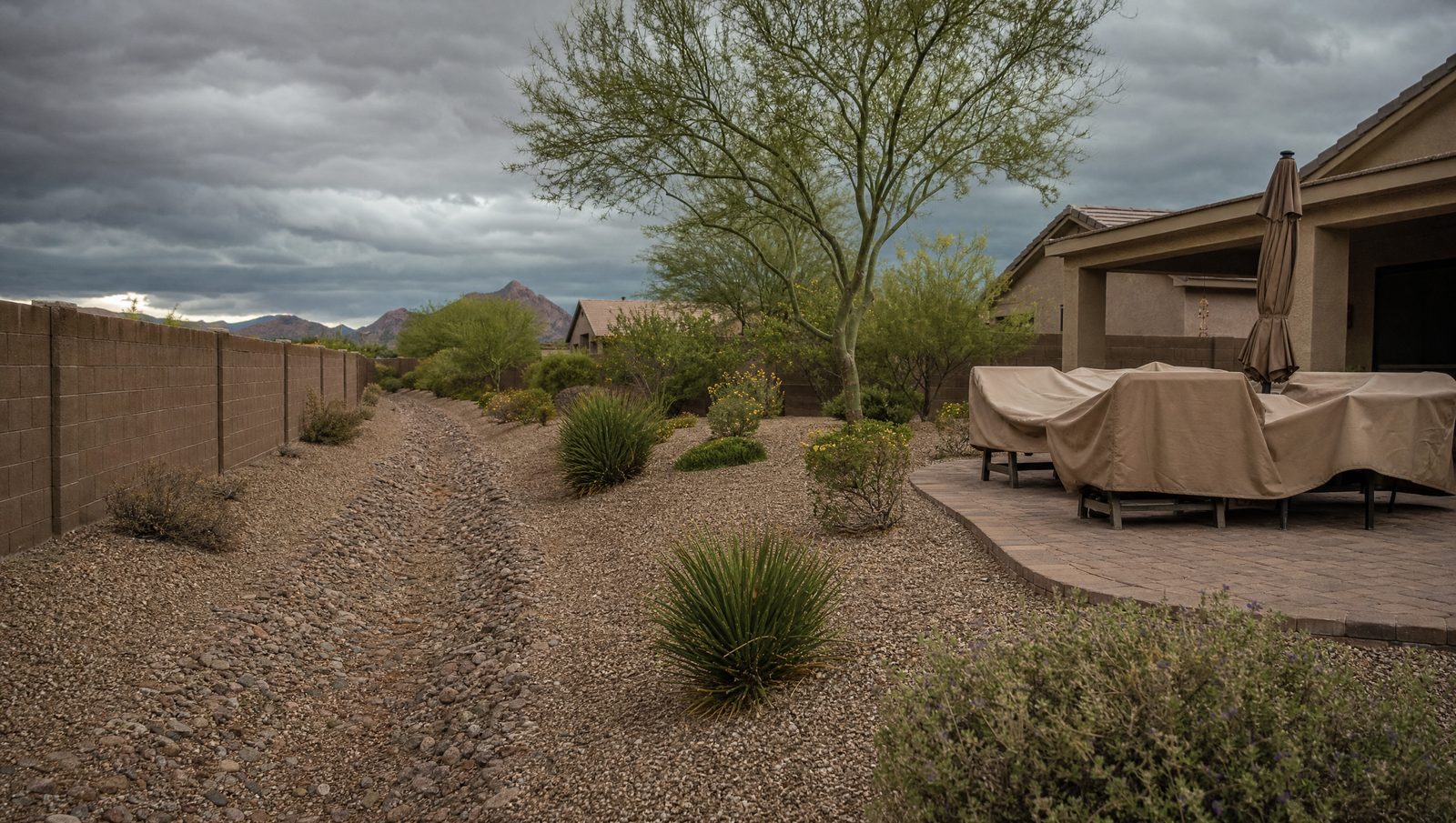 Cleared drainage swale with patio furniture secured ahead of monsoon storms