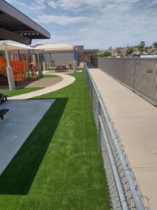 Synthetic turf strip installed along a fence line at a Phoenix-area playground