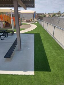 Artificial turf wrapping a covered picnic area and concrete walkway