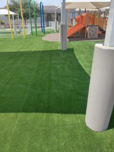 Wide artificial turf play area with slides and climbing structure